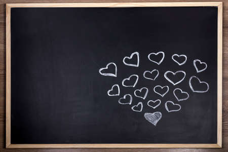Hearts drawn in white chalk on a blackboard, background image with copy spaceの写真素材