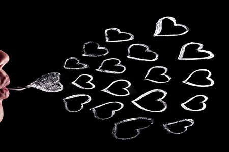 women's lips release hearts drawn in chalk on a blackboard, love backgroundの写真素材