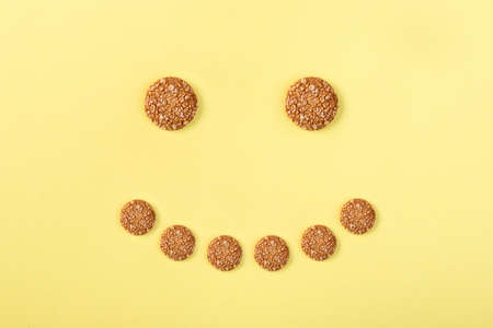 oatmeal cookies laid out as a smiley on a yellow backgroundの写真素材