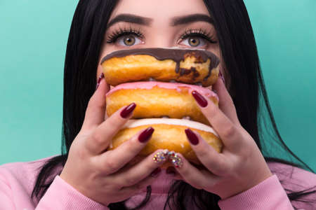 a portrait of a plus-size model covered her face with donuts and a picture on an azure background...