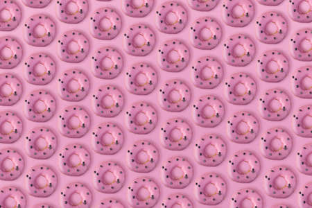 many donuts with a icing on a pink backgroundの写真素材