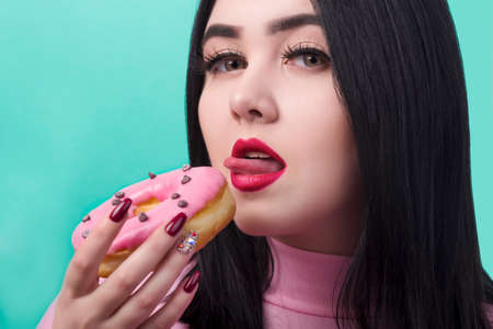woman with red lips with donuts in her hand prepare to eat it and lick it, on azure backgroundの写真素材