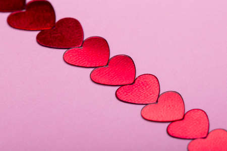 small decorative red hearts on a pink backgroundの写真素材