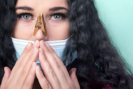 girl with a clothespins on the nose in a protective medical mask, the concept of cold and runny noseの写真素材