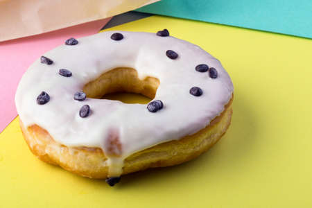 donut with white icing on a colorful backgroundの写真素材