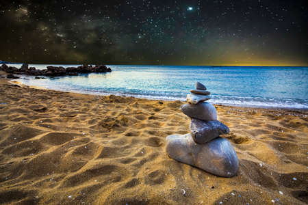 stone cairn on the sand beach, on the backgroundÂ of night star landscape, concept of balanceの写真素材