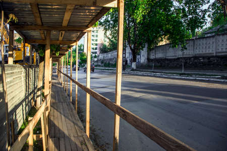 pedestrian crossing with a canopy of corrugated metal gray sheet metal and wooden floor along the construction site with a dangerous zoneの写真素材