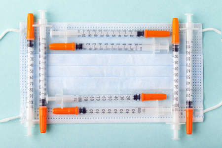 insulin syringes in the form of a frame on a protective blue maskの写真素材