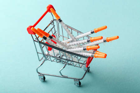 insulin syringes in red cart trolley on blue backgroundの写真素材