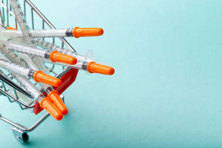 insulin syringes in red cart trolley on blue backgroundの写真素材