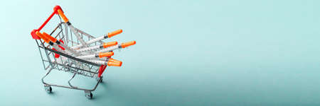 insulin syringes in red cart trolley on blue background, concept screen saver for medical siteの写真素材