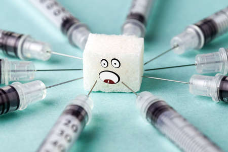 insulin syringes stuck in a scared sugar cube, diabetes treatment conceptの写真素材