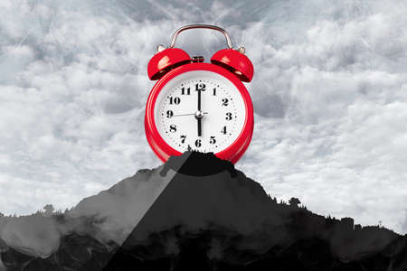 mountain with a red clock with an alarm on top, concept of a cheerful morning
