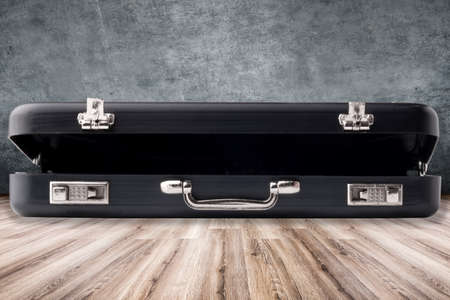 ajar black modern case on a laminate floor on a concrete wall backgroundの写真素材