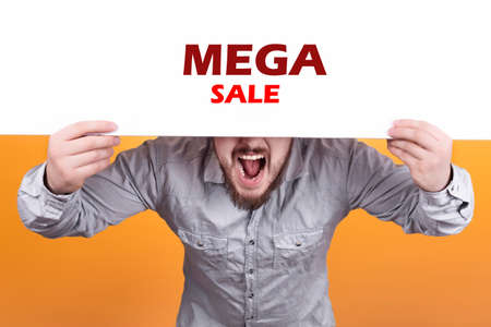 a man holding a poster with the inscription mega sale, expressive shouts and inviting buyersの写真素材