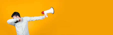 man in dub dance pose with a megaphone in his hand turns him away, concept of reluctance to protest, image on orange backgroundの写真素材