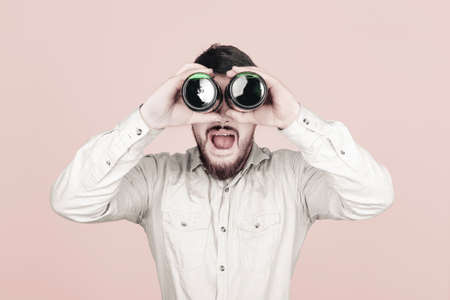 surprised man with bottles of beer in the form of binoculars on a pink background