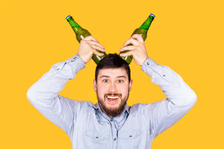 funny charismatic bearded man with horns bottles on yellow background