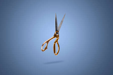 levitating golden tailor scissors on a blue backgroundの写真素材