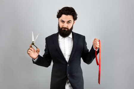 bearded man holding  red ribbon and scissors over gray background, Grand Openingの写真素材