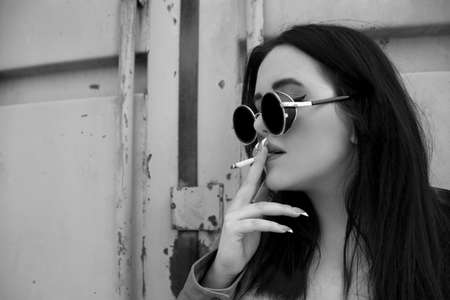 women in depression smoking a cigarette, woman in trendy round sunglasses, black and white imageの写真素材