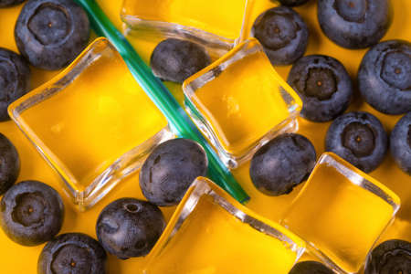 ice cubes and blueberries over yellow backgroundの写真素材