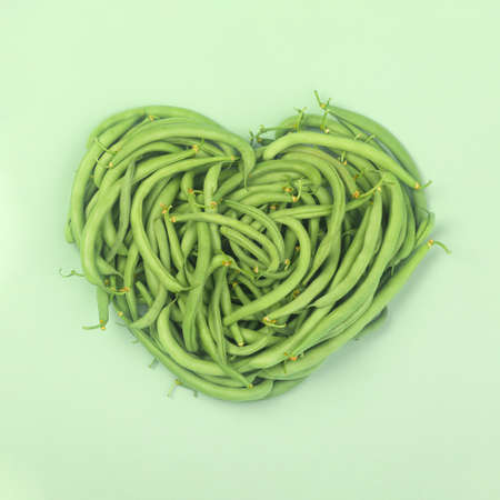 Heart of green beans on green background,  top view.の写真素材