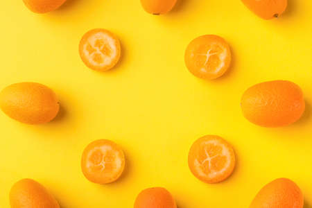 Flat lay pattern of fresh kumquats on a yellow  background. Top view, kumquats mock-up