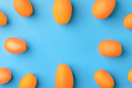 Flat lay pattern of fresh kumquats on a blue  background. Top view, kumquats mock-up