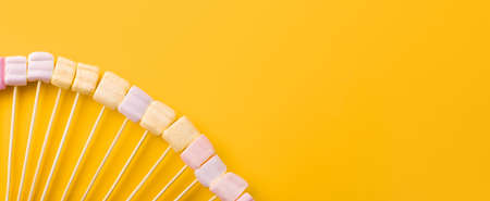 marshmallows on wooden sticks, over yellow background, panoramic mock-up