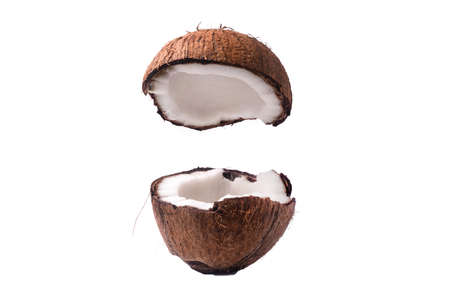 Two coconut section halves isolated on white background one broken in two brown fibrous shell with milk meatの写真素材