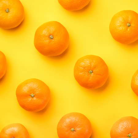 Fruit pattern of fresh orange tangerine or mandarin on yellow  background. Flat lay, top view. Pop art design, creative summer concept. Citrus in minimal style.の写真素材