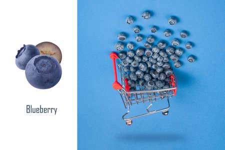 Creative layout made of  turned metal shopping trolley filled with blueberries over blue background, vegetarian healthy food conceptの写真素材