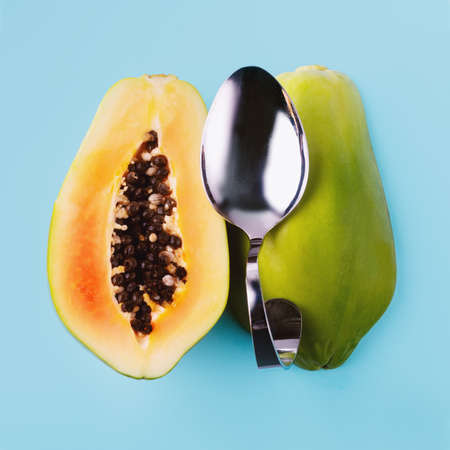 Half sliced papaya and dessert spoon on blue background, vegetarian food concept.の写真素材