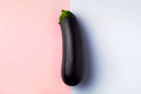 Fresh raw dark purple eggplant on blue pink background, the concept of vegetarianismの写真素材