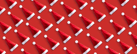Creative Santa Claus hat pattern over red  background. Minimal winter flat lay Christmas concept, panoramic imageの写真素材