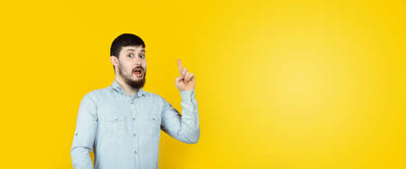 Photo of caucasian man  reliable person got new brilliant idea, startup raise finger, wear jeans...