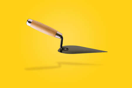 Triangle trowel over yellow background, new construction tool conceptの写真素材
