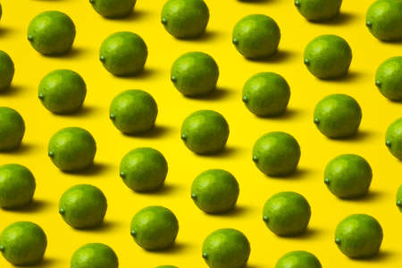 pattern with limes on yellow background. Minimal flat lay food textureの写真素材