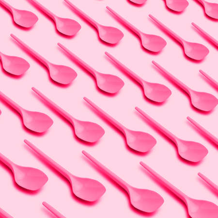 Flat lay photo of pink plastic spoons of recyclable plastic. Creative top view pattern. On pink background.の写真素材
