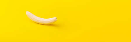 peeled banana on yellow background, minimal diet concept, panoramic mock-up with space for textの写真素材