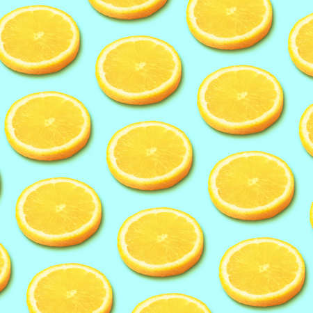Trendy pattern made with yellow lemon slice on light blue background. Minimal summer concept.の写真素材