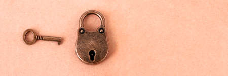 bronze lock and key on an orange  background, panoramic image with space for textの写真素材