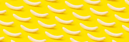 Ripe peeled bananas on yellow background, minimal diet concept, panoramic patternの写真素材