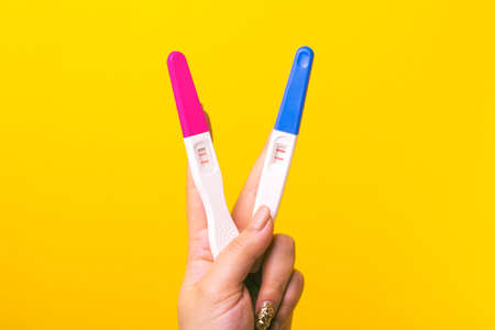 Pregnancy tests in hand over yellow backgroundの写真素材