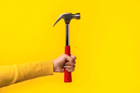 hammer in female hand over yellow backgroundの写真素材