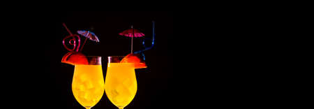 two orange cocktails with ice on a dark background, concept of summer refreshments, panoramic mock-upの写真素材