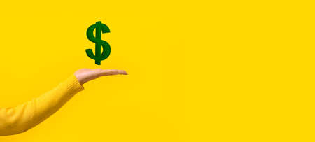 3d Green dollar sign on a woman's hand over yellow background, panoramic mock-upの写真素材