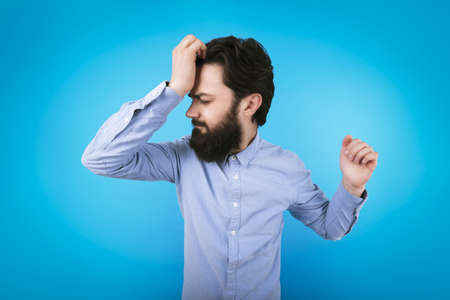 bearded man holds his hand to his forehead, concept of fatigue