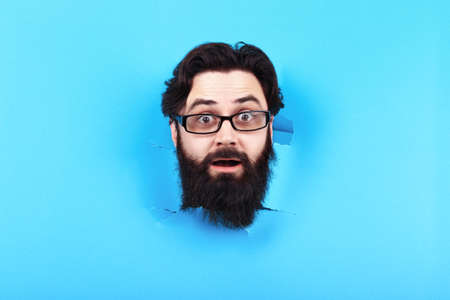 surprised bearded man in hole in the blue backgroundの写真素材